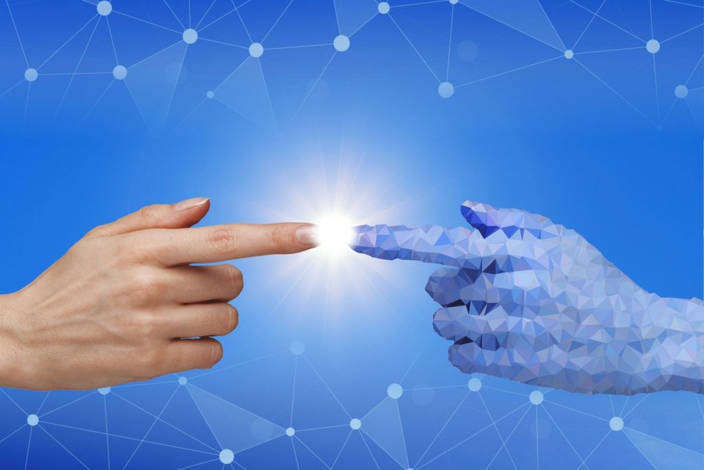 A human hand touches a imaginary computer hand to indicate artificial intelligence